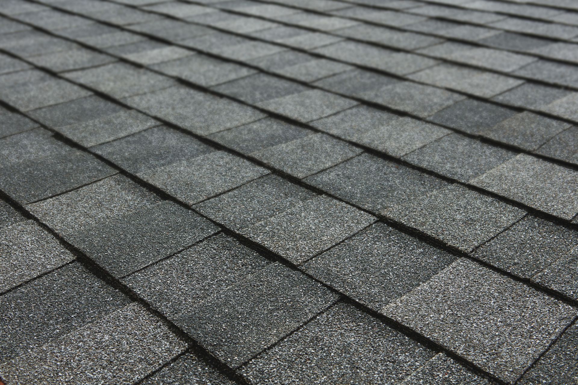 Gray shingled roof viewed at an angle, showing overlapping asphalt shingles