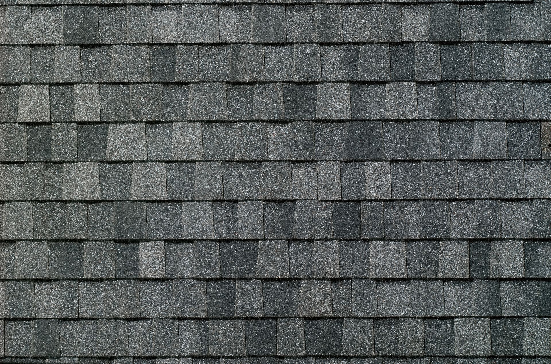 Close-up of gray asphalt shingles arranged in a staggered roof pattern.