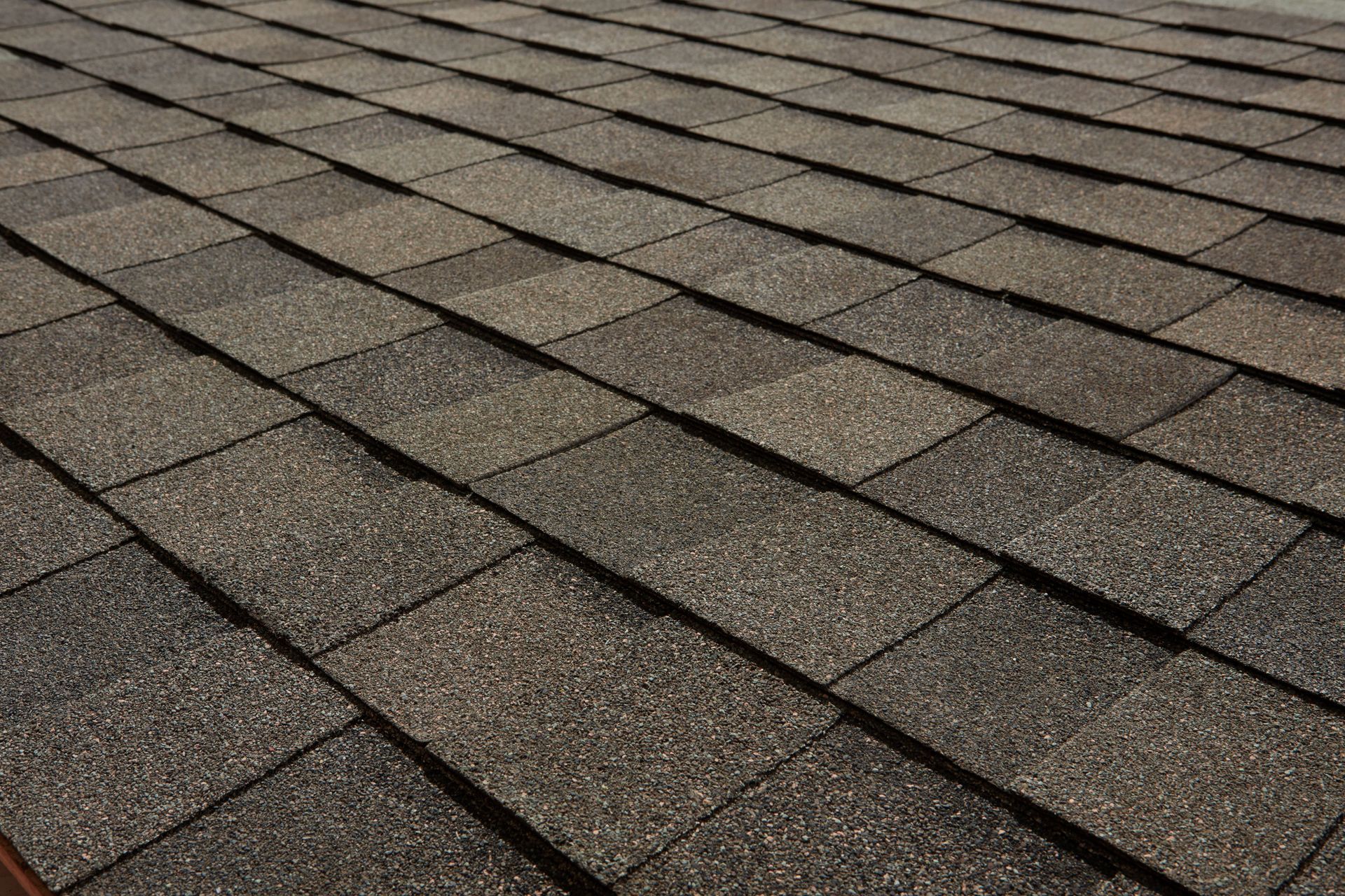 Close-up of a gray asphalt shingle roof with overlapping rows