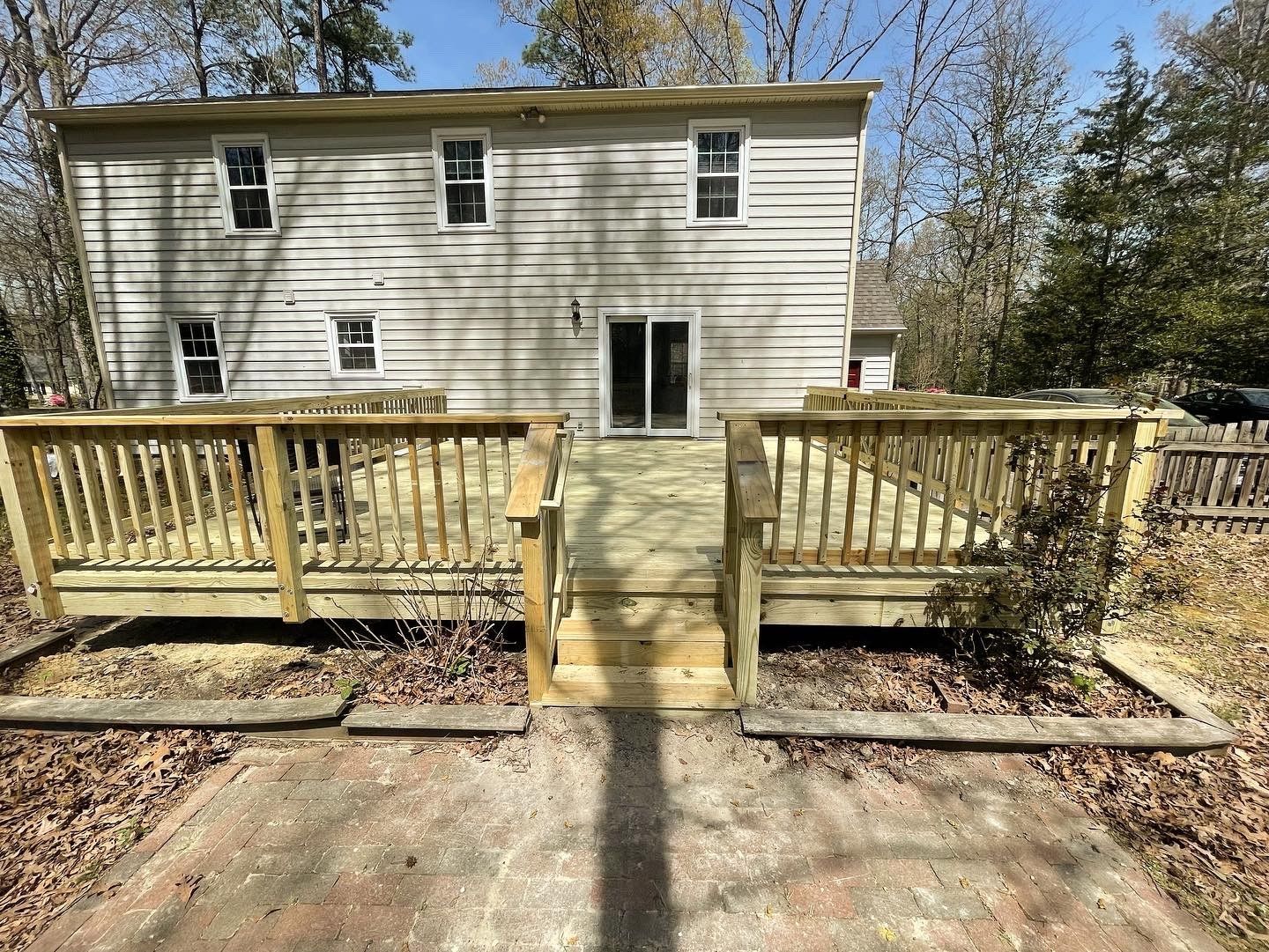 Backyard wooden deck with steps leading to a beige two-story house