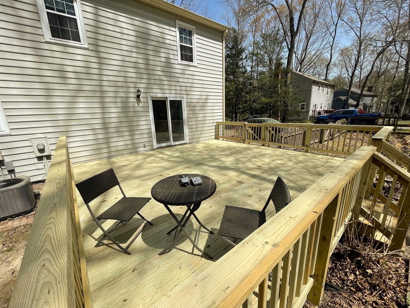 Backyard wooden deck with two folding chairs and a small round table beside a house