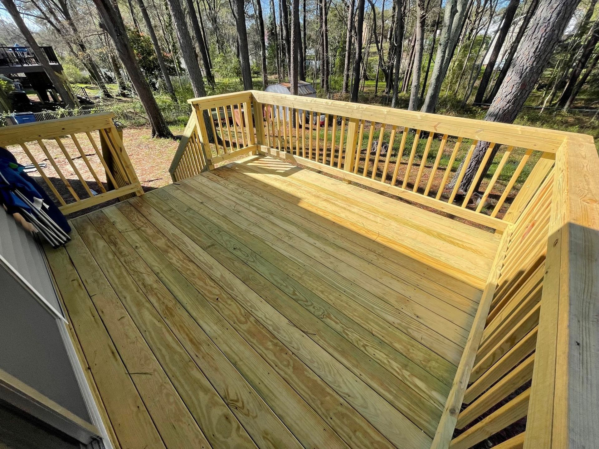 Wooden deck with fresh railings and forest view under construction