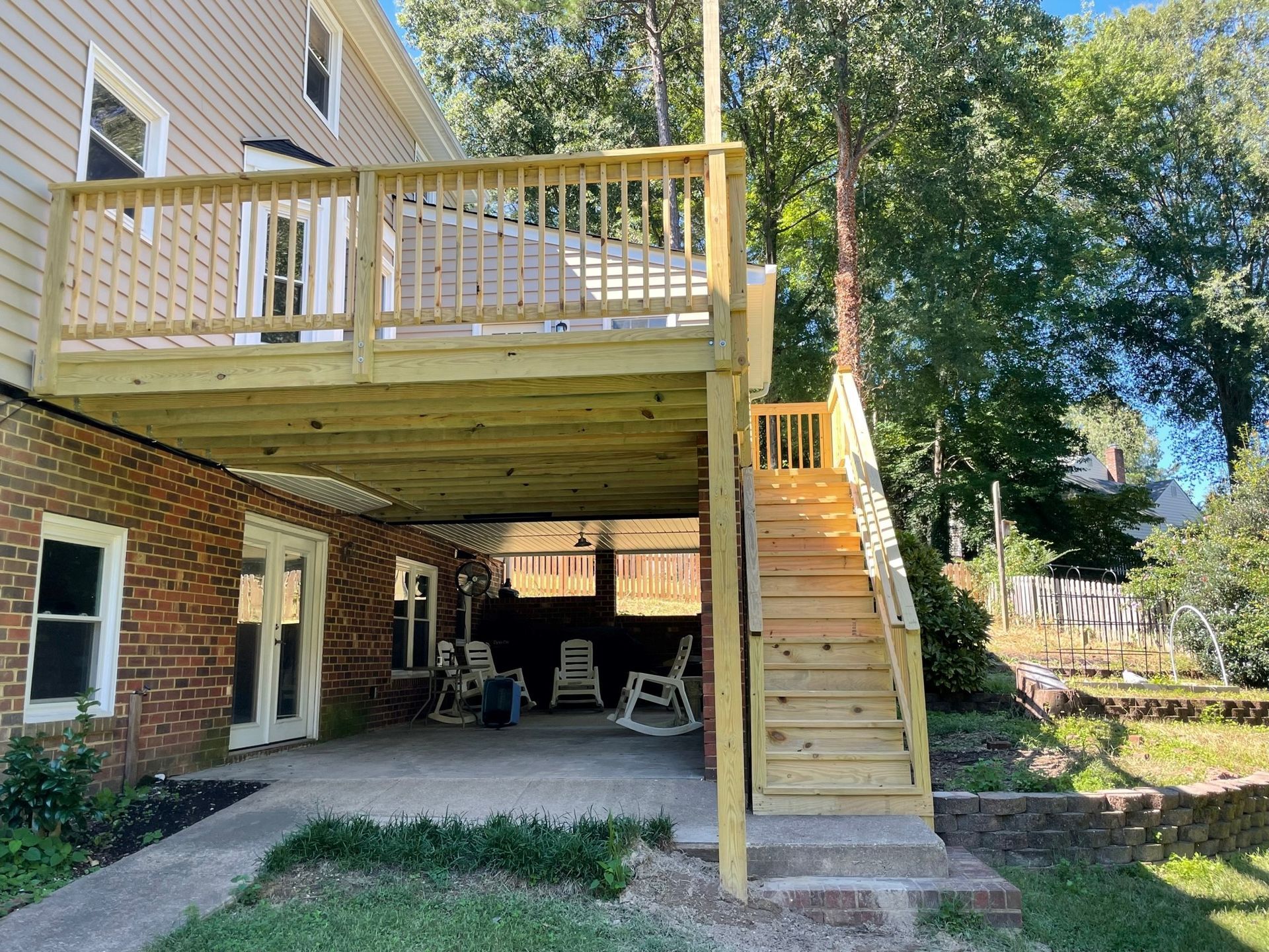 Back deck with wooden stairs over a covered patio beside a house