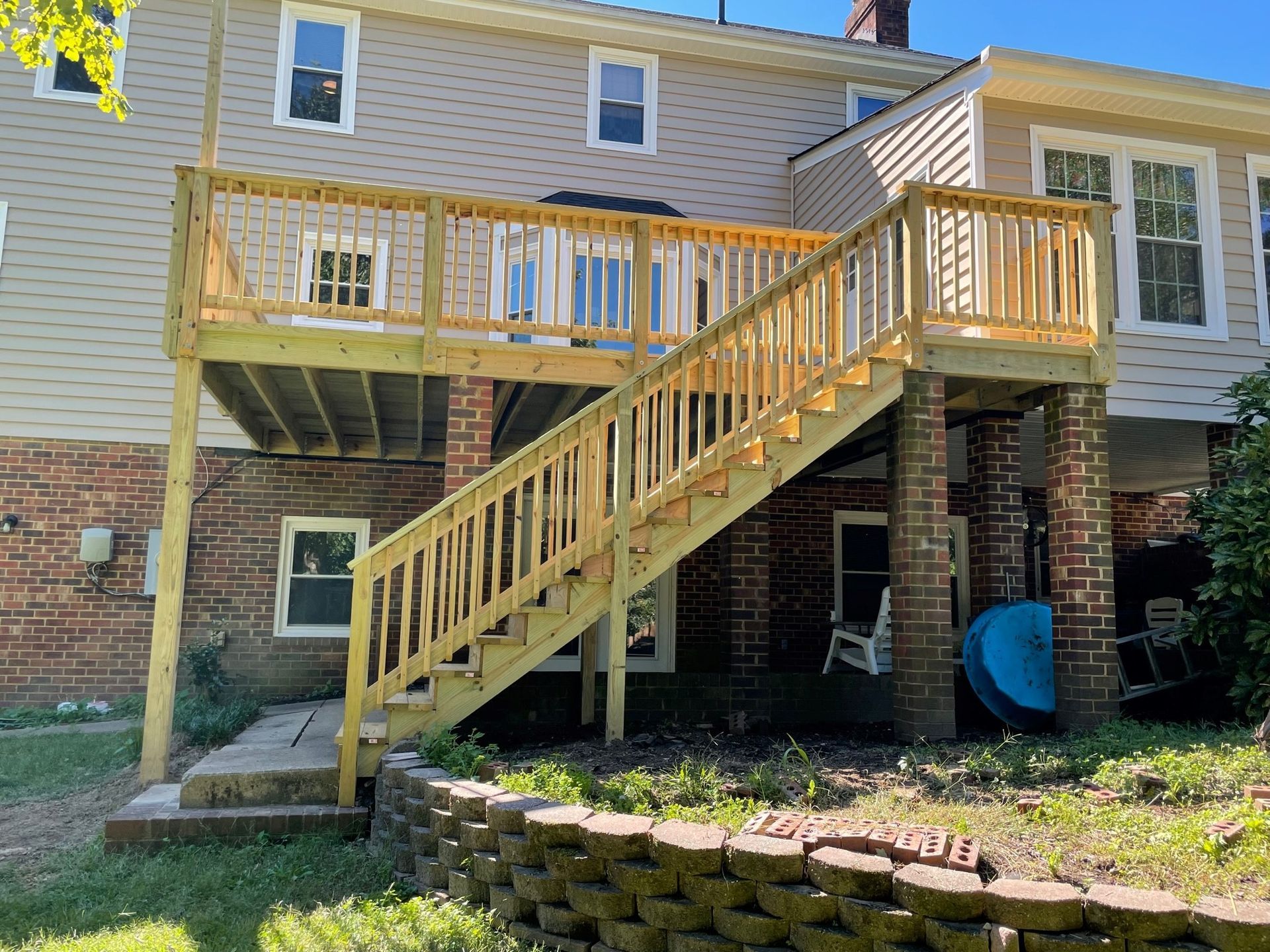 Backyard deck with wooden stairs attached to a brick-and-siding house.