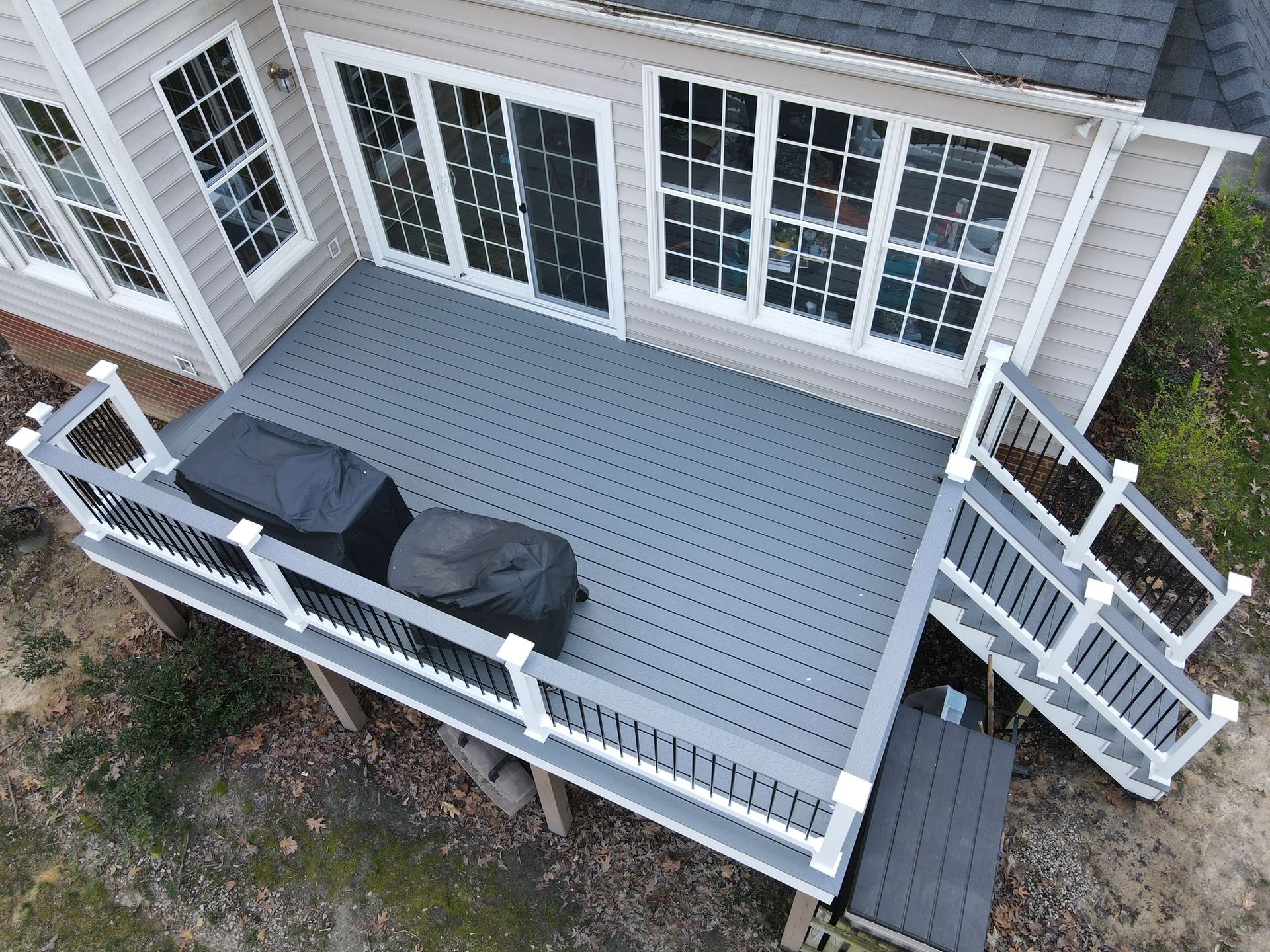 Back deck with white railings, gray flooring, outdoor furniture, and stairs leading to the yard