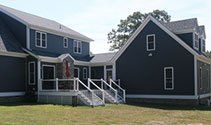 Dark blue house with white trim and a small front porch and ramp