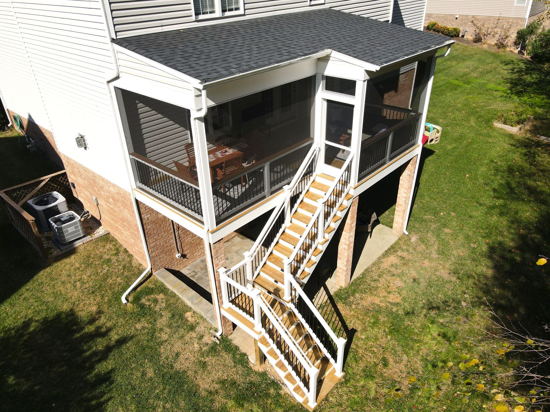 Back porch with white railings and stairs descending to a grassy yard beside a house