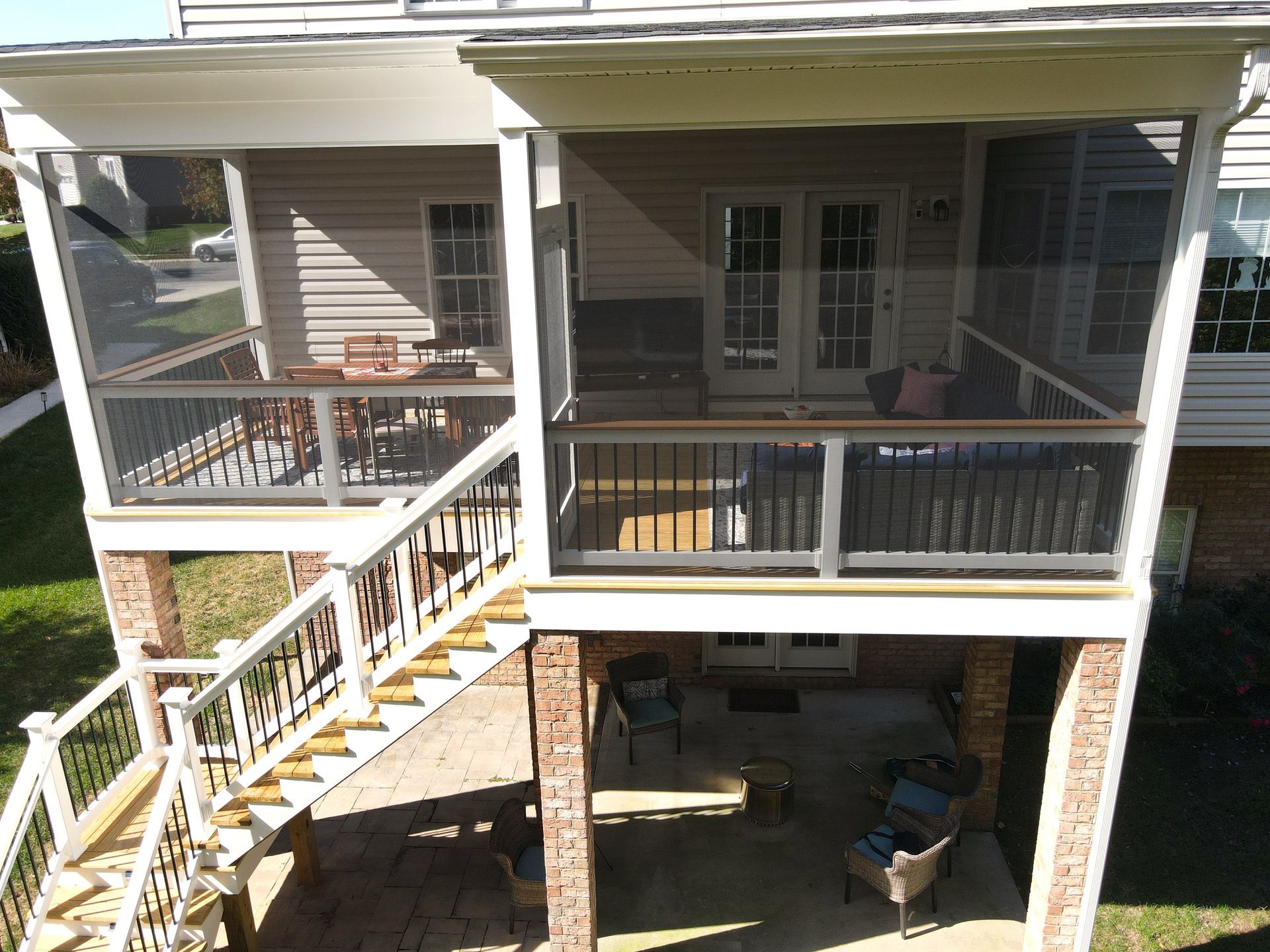 Front porch and upper balcony of a beige house with white railings and stone columns