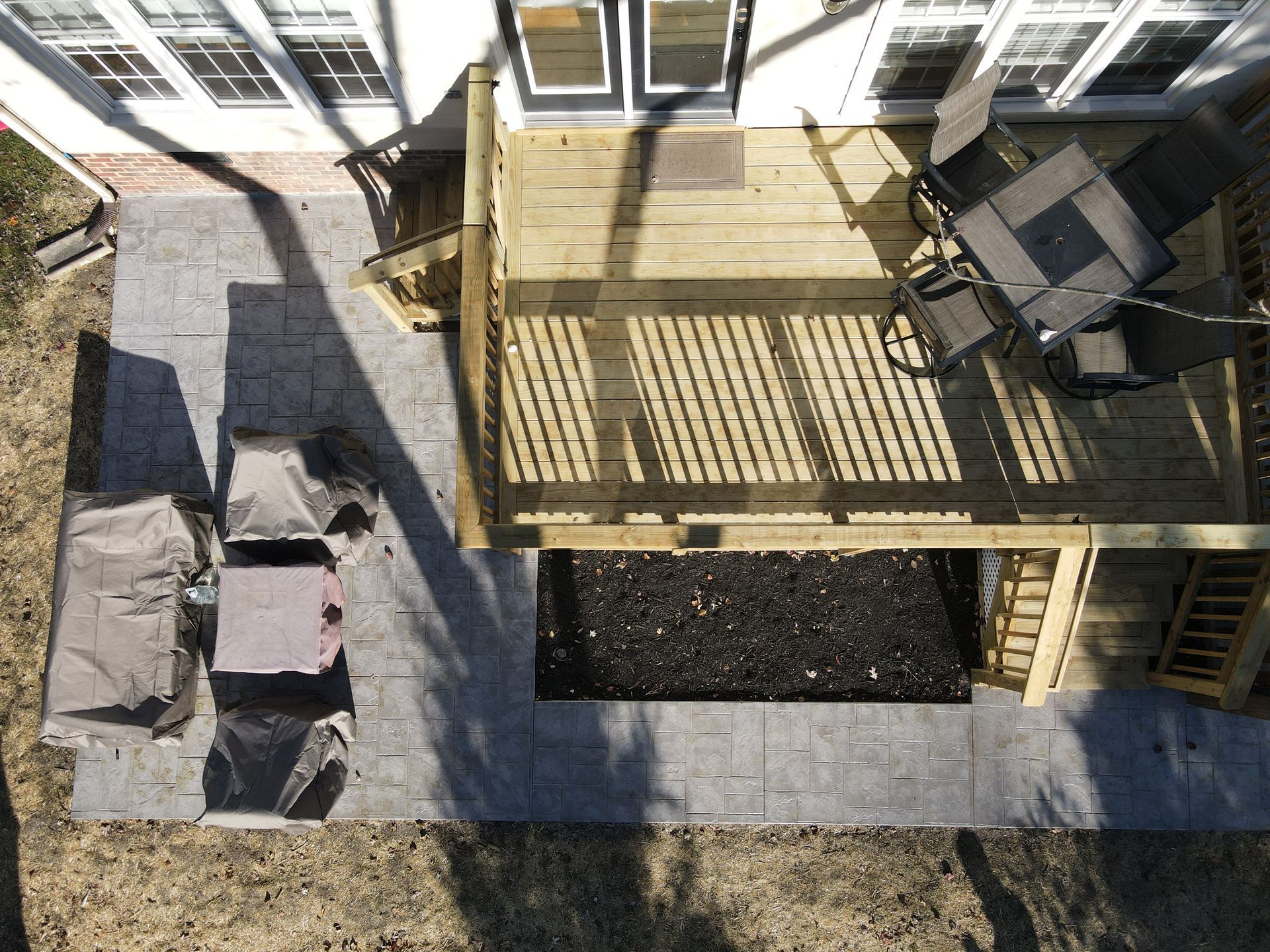Overhead view of a backyard deck, patio, and outdoor furniture beside a house.