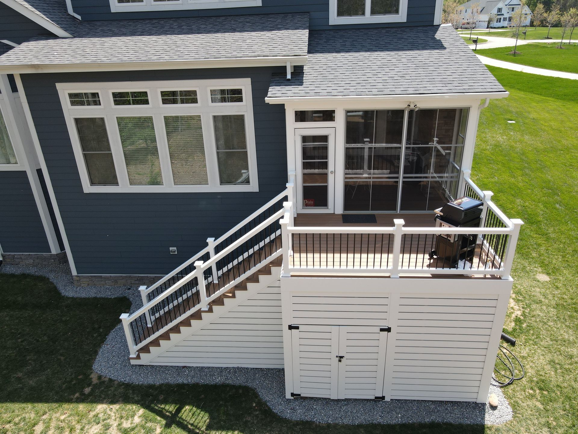 Backyard deck with white railing and stairs attached to a dark blue house