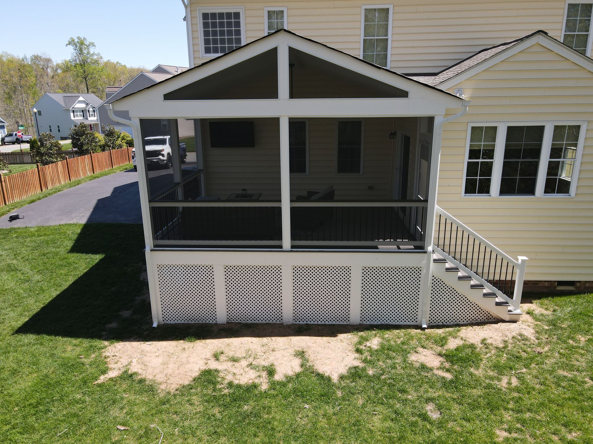 Back porch screened-in gazebo attached to a yellow house, with white trim and stairs on the right.
