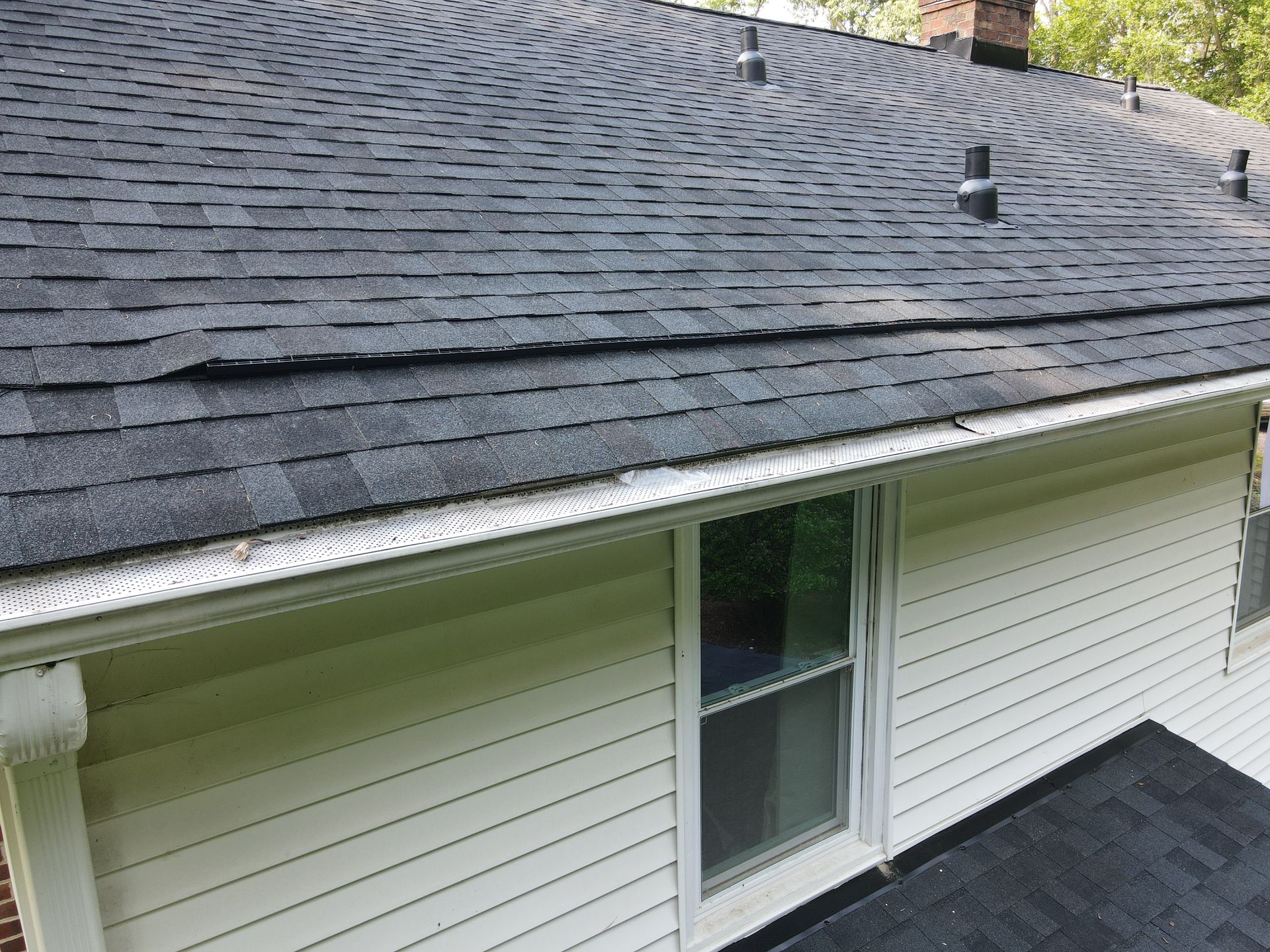 House exterior with gray shingle roof, white siding, and a window below the eaves