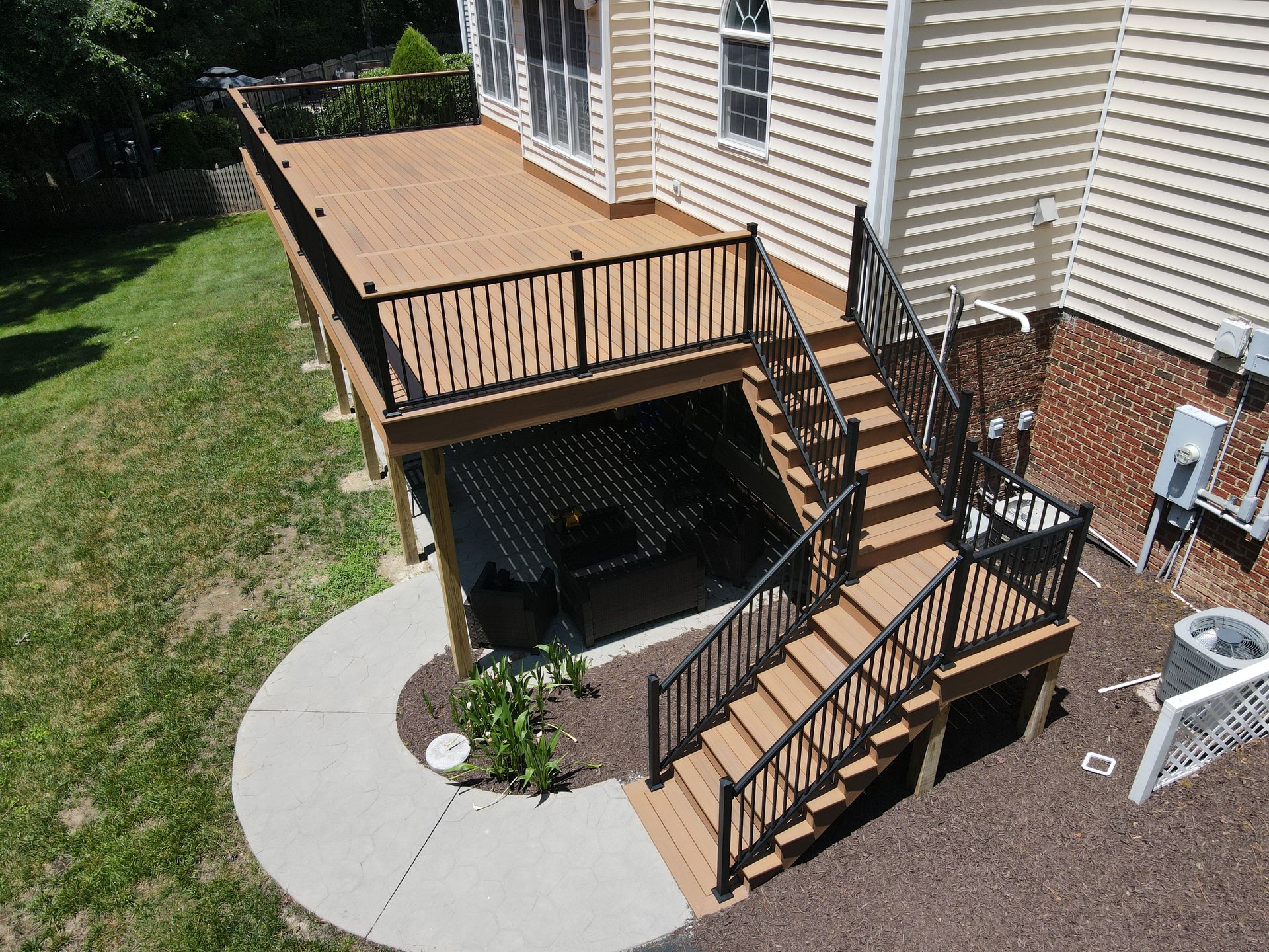 Backyard deck with stairs, railing, and a lower patio beside a house