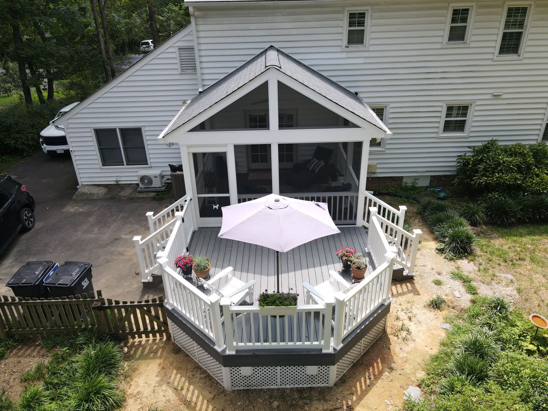 Backyard white deck with umbrella and chairs attached to a house