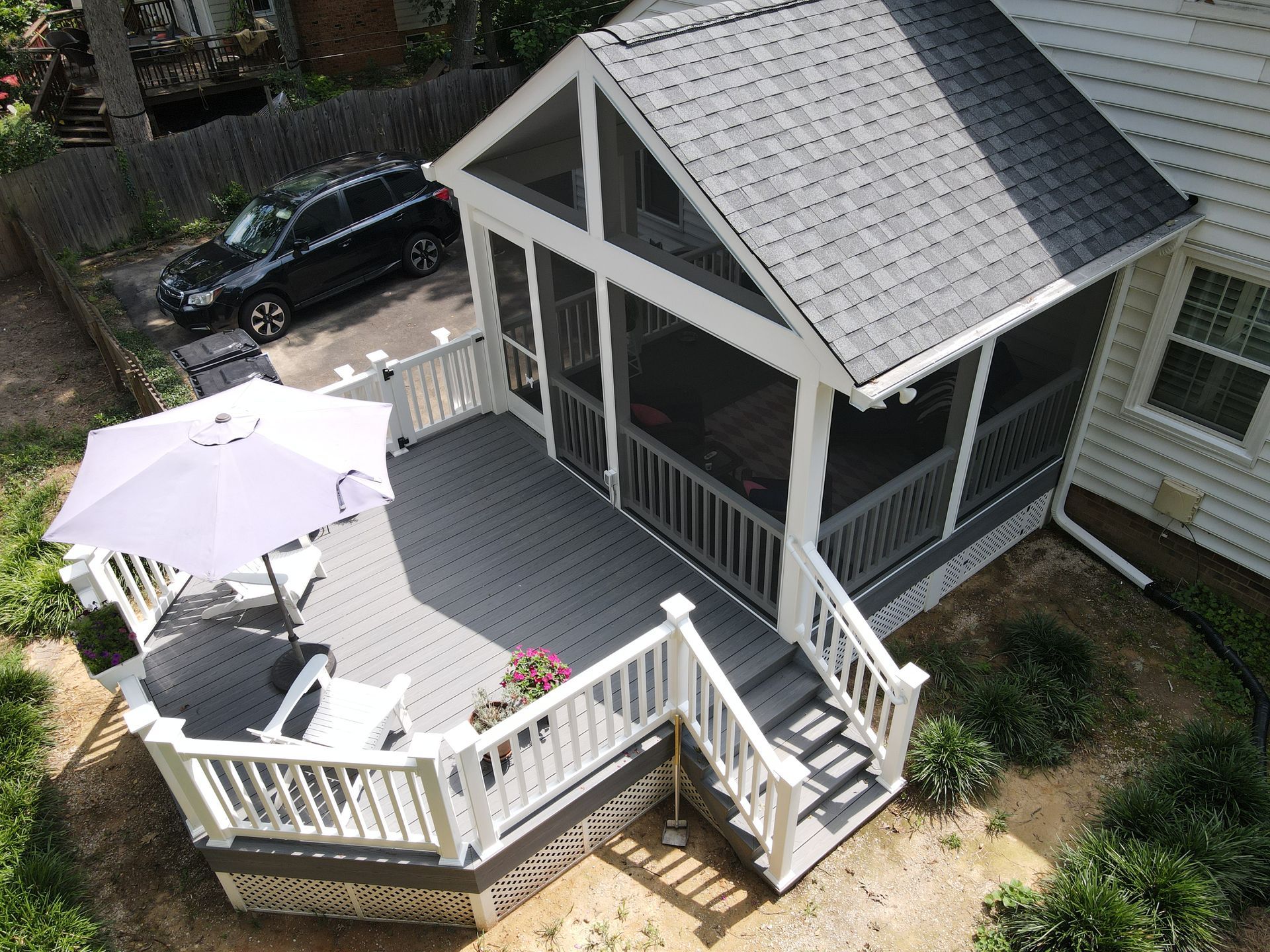 Back deck with white railings, gray roofed porch, stairs, and a patio table with umbrella