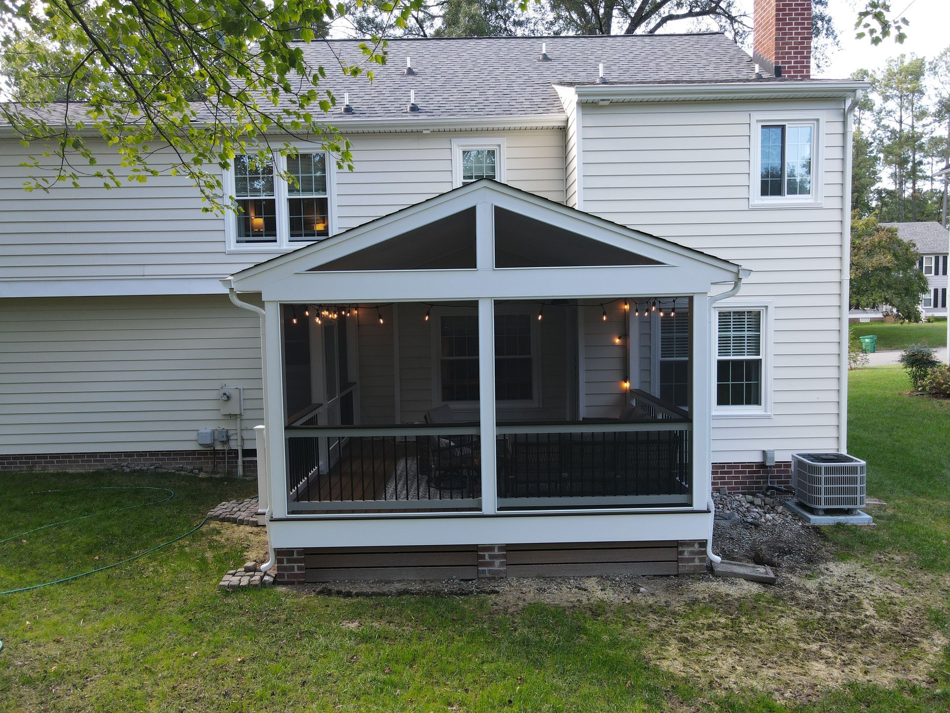 White house with a small screened porch and gray roof in a grassy yard