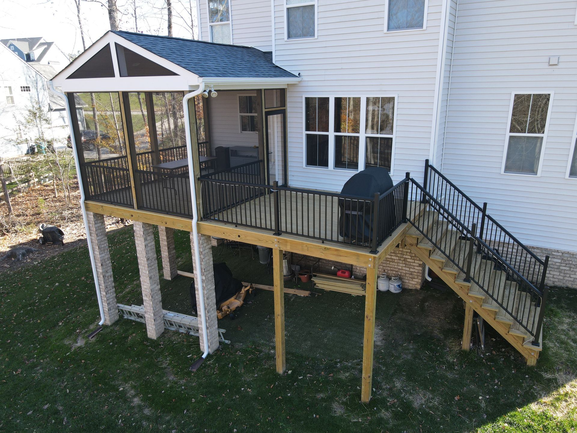 Back porch deck with stairs, screened gazebo, and black railing on a white house