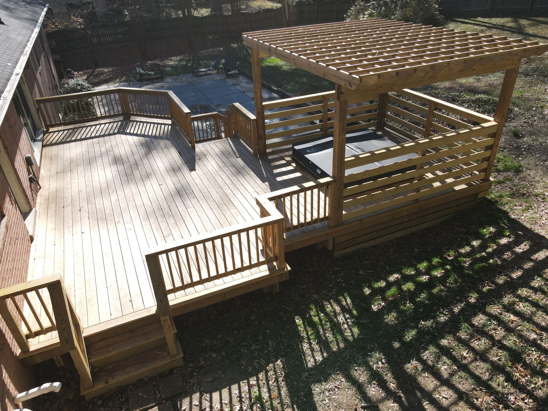 Wooden deck with a pergola and railing beside a yard, seen from above