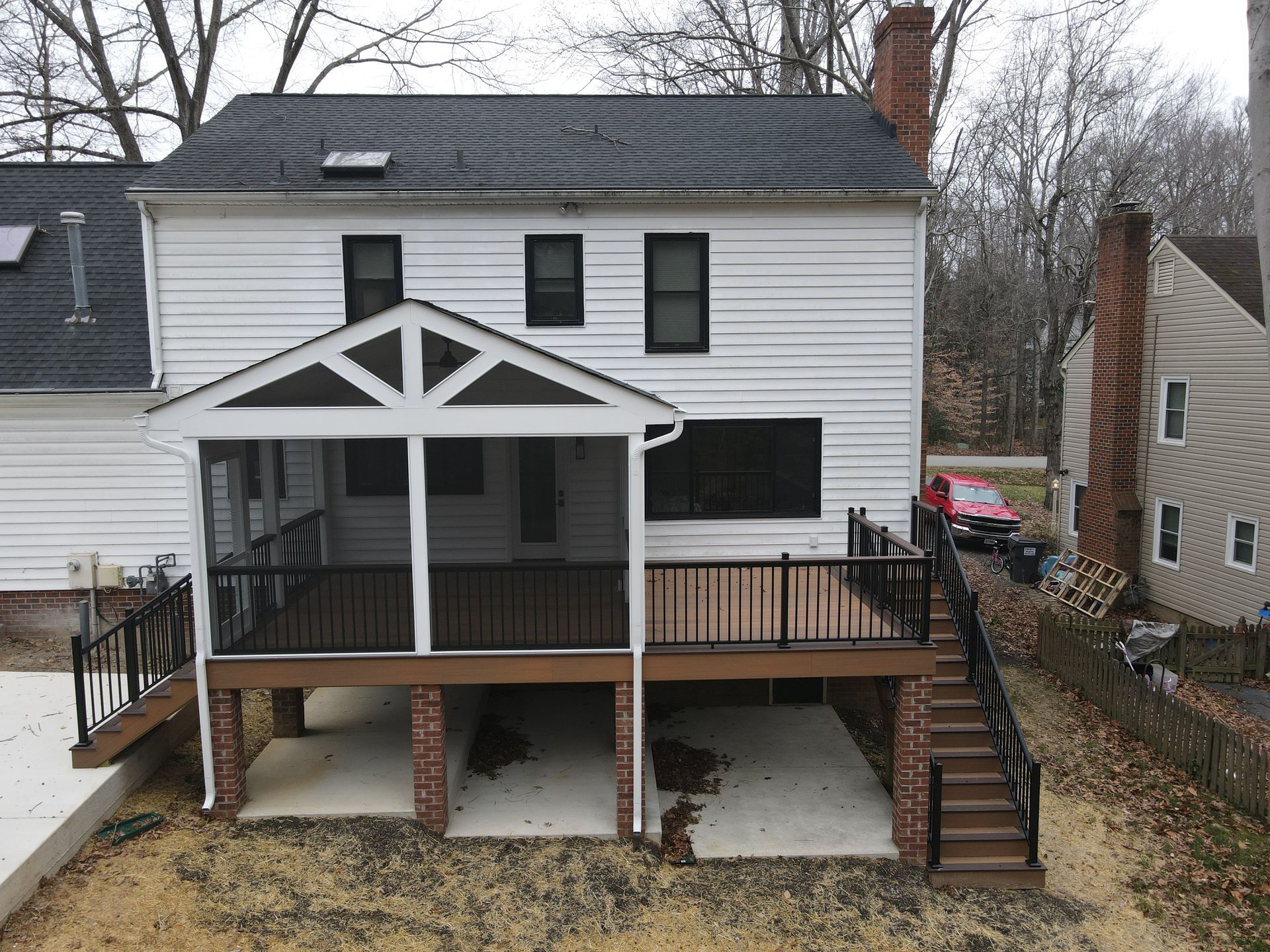 Two-story white house with a raised wooden deck and stairs in the backyard