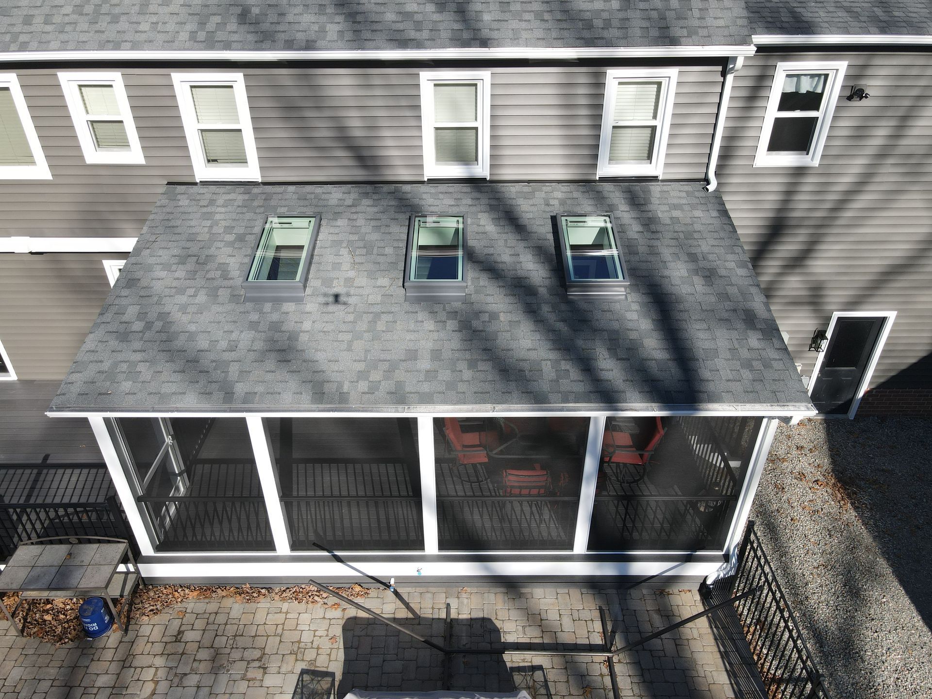 Back porch with white railing and screened windows under a gray roof beside a house