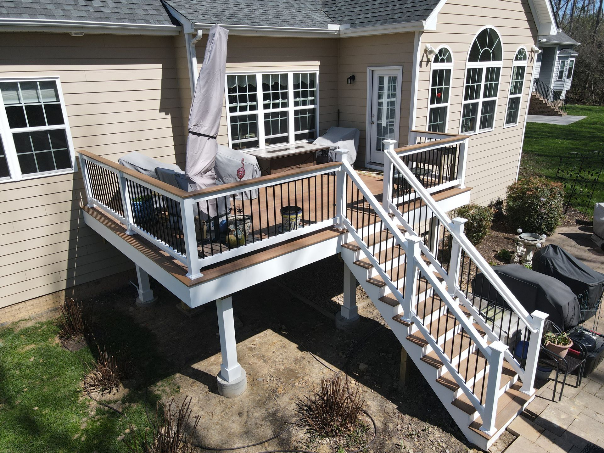 Raised wooden deck with white railing and stairs attached to a beige house