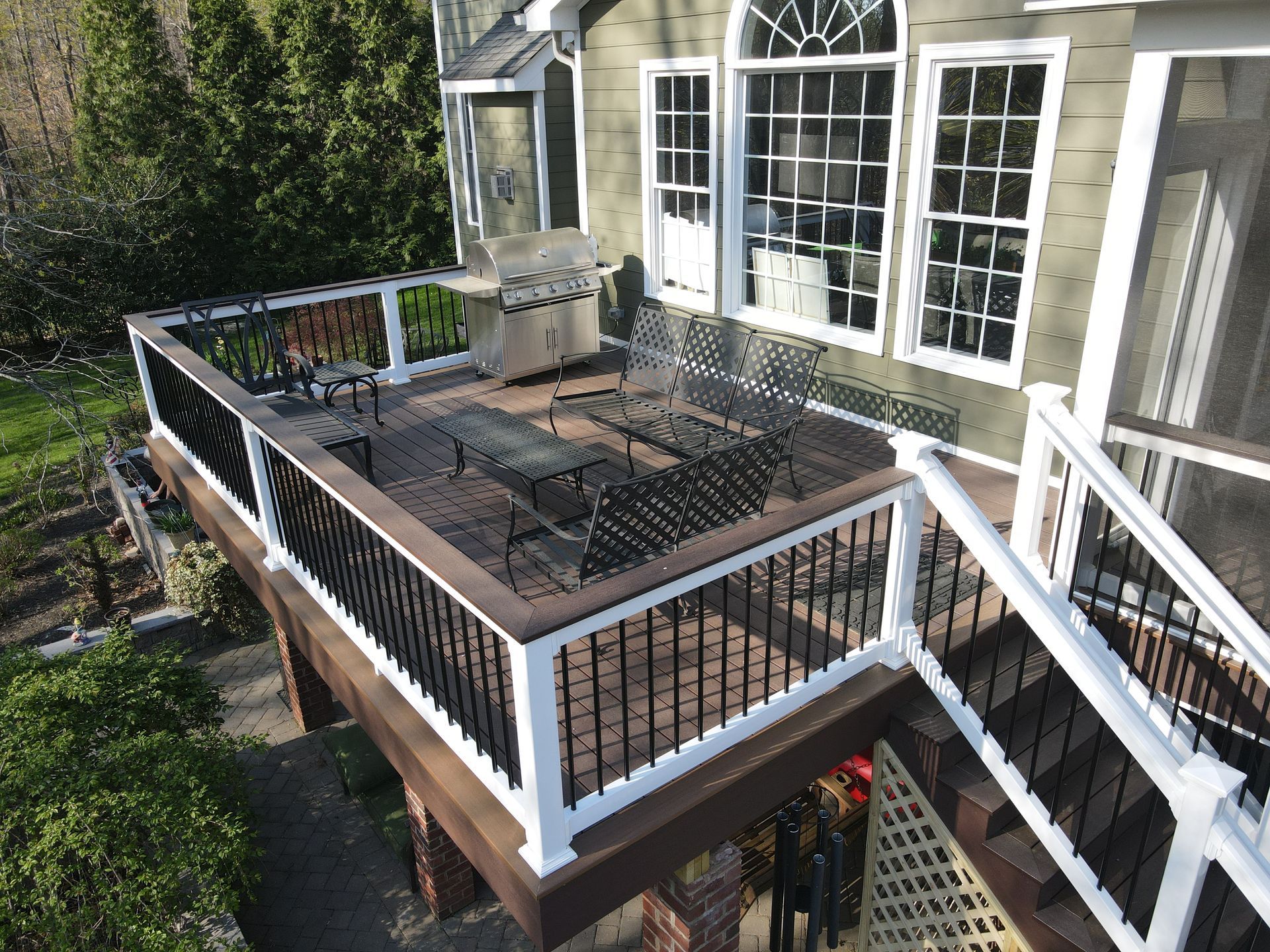Outdoor wooden deck with black railing, patio furniture, and white French doors beside a house