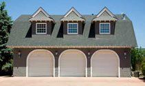 Three-car garage with dormer windows and arched white doors on a suburban house.