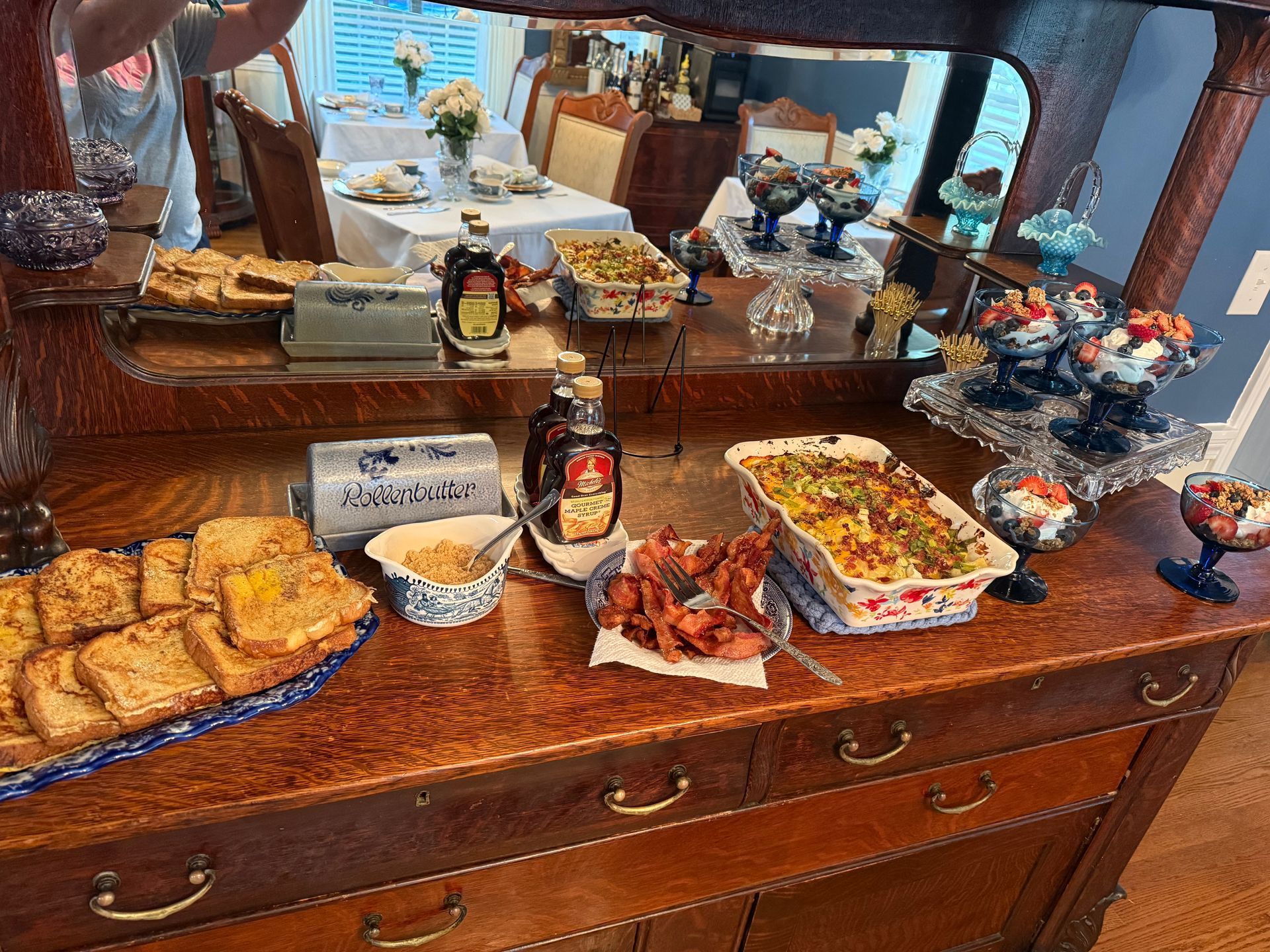 Buffet table with pastries, fruit, and drinks arranged on a wooden dresser