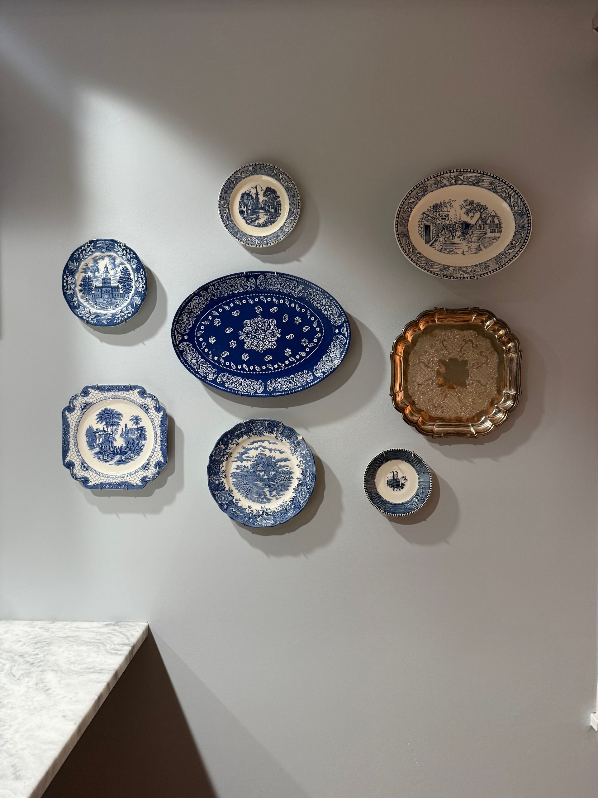 Decorative blue-and-white plates arranged on a gray wall above a staircase corner