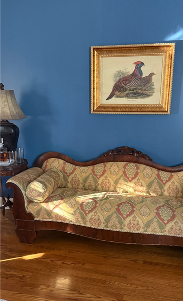 Vintage sofa beneath rooster painting on a blue wall in a living room