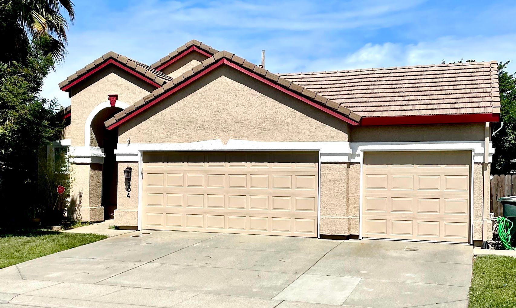 A house with three garage doors and a red roof