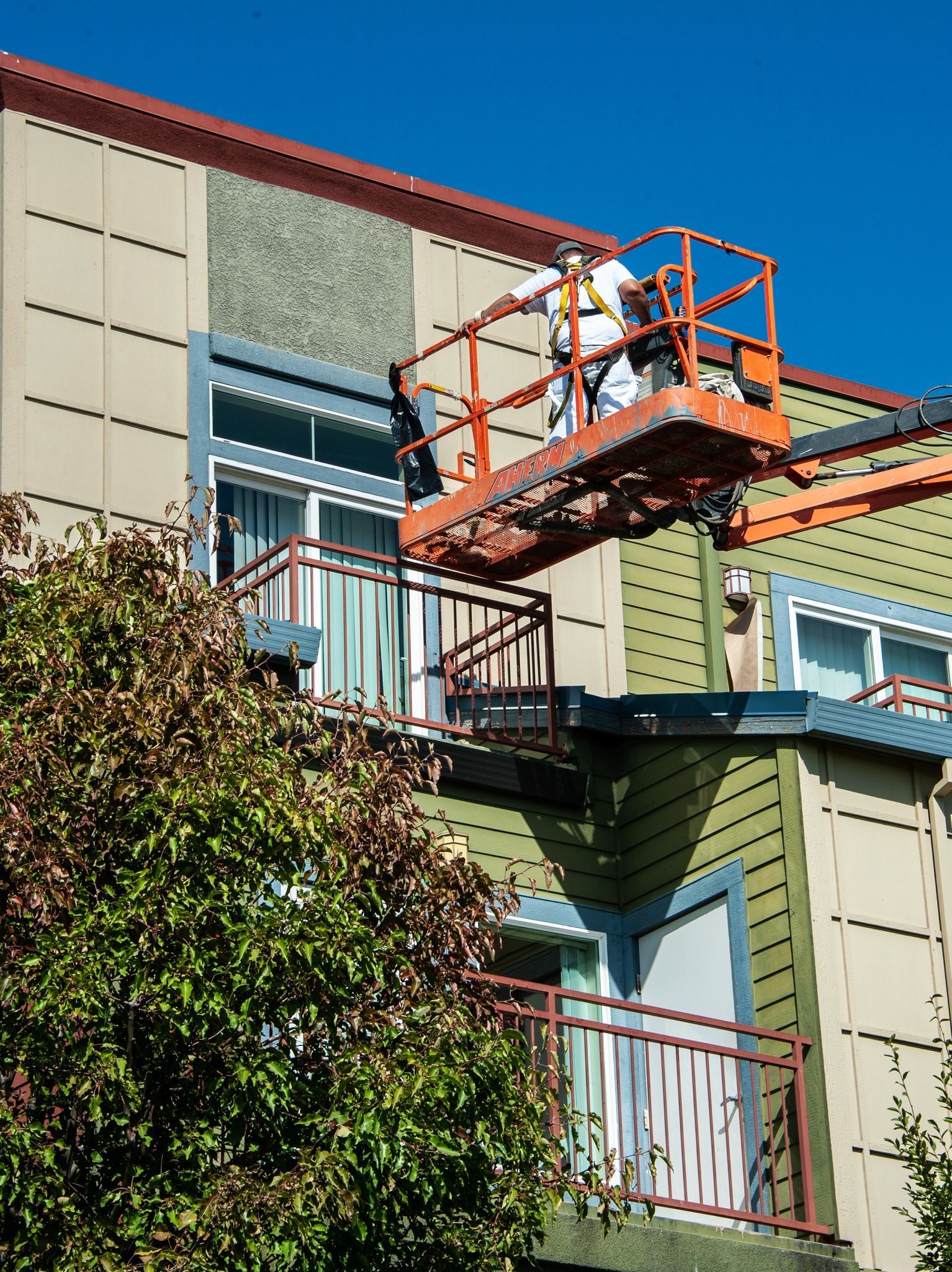 A man on a lift is painting the side of a building