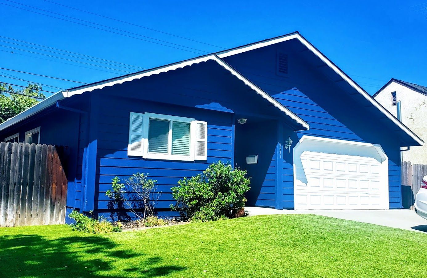 A blue house with a car parked in front of it