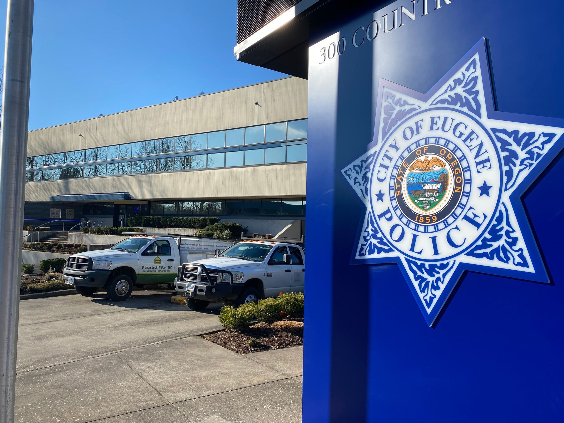 Eugene Police Department sign with building and vehicles.