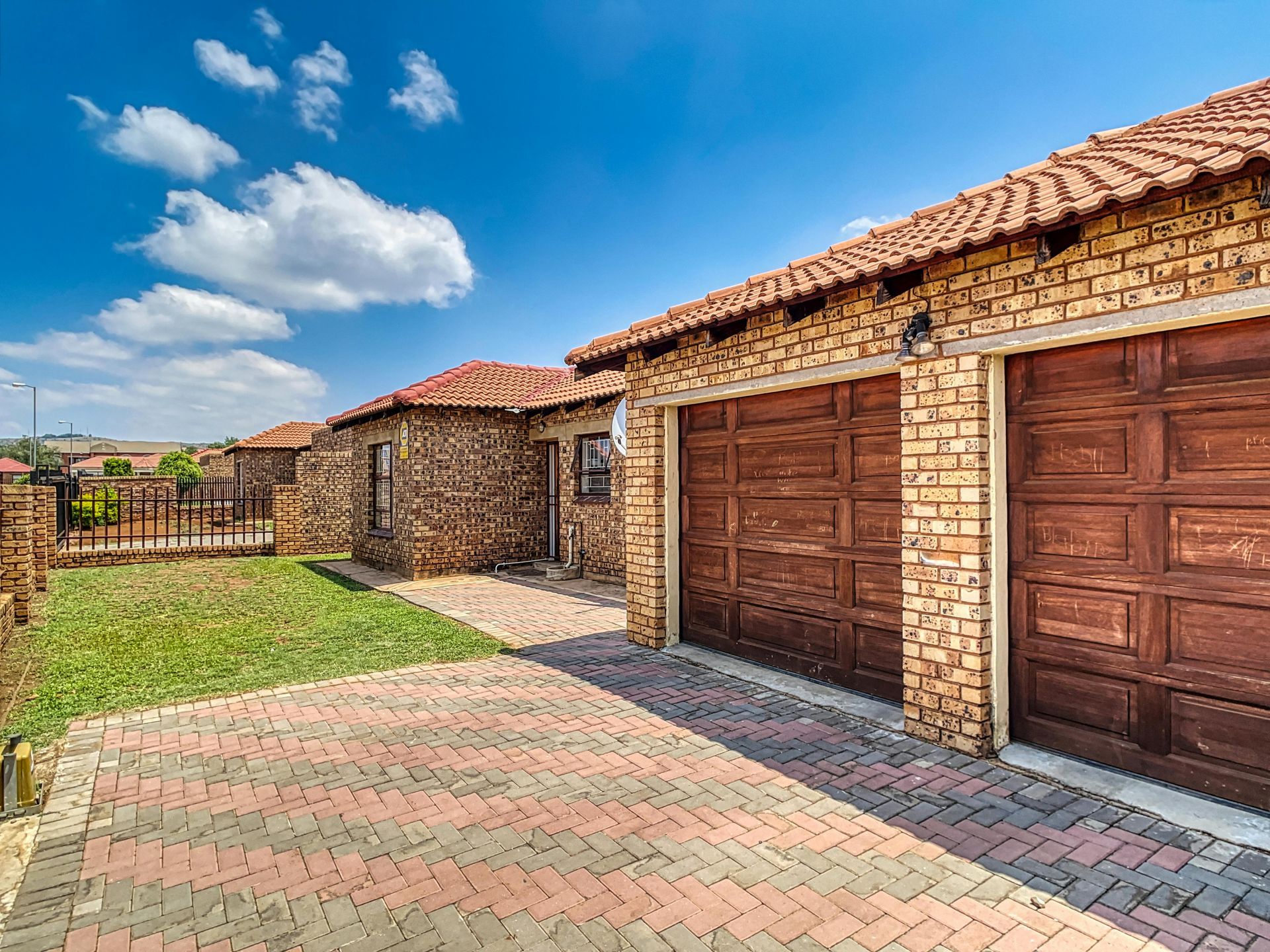 A brick house with two garage doors and a brick driveway.