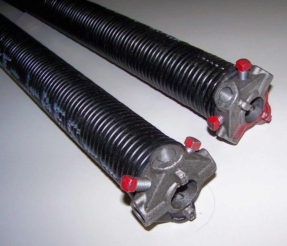 Two black coiled garage door springs with silver end fittings and red adjustment knobs