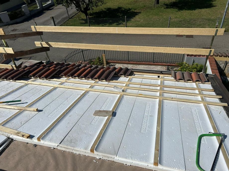 Costruzione del tetto: pannelli isolanti, travi in legno e tegole in terracotta.
