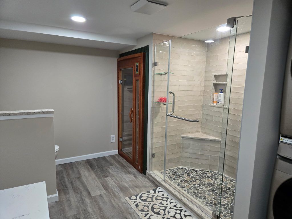 Modern bathroom with a glass shower, gray walls, wood-look floor, and pebble shower base.