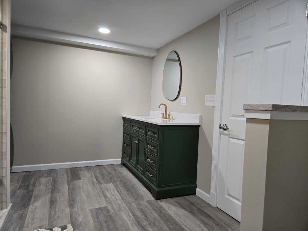 Empty hallway with gray walls, wood-look flooring, white doors, and a dark green vanity with mirror
