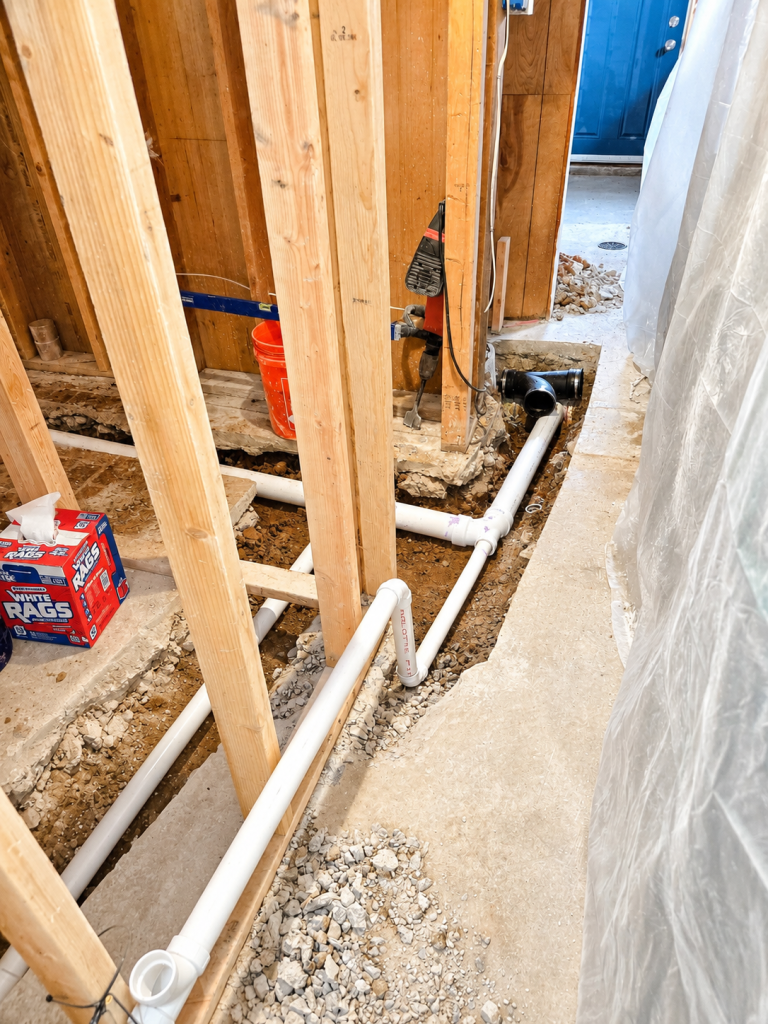 Exposed plumbing pipes in an unfinished interior wall under construction with a blue door in the background