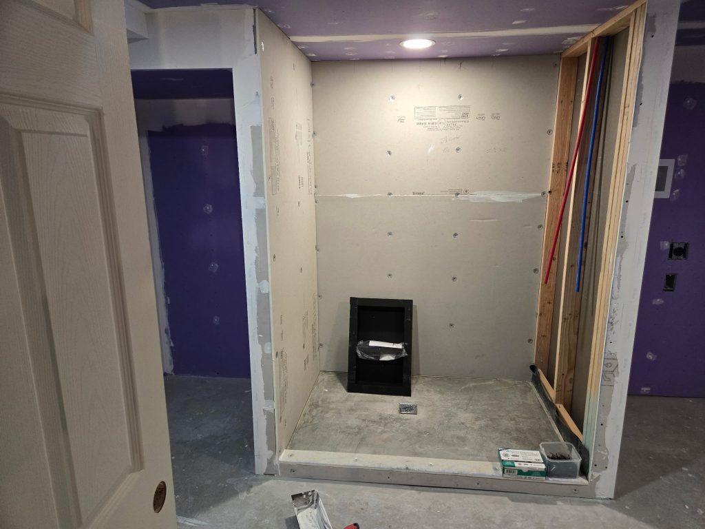 Partially renovated room with purple walls, unfinished drywall, and a small black heater on the floor