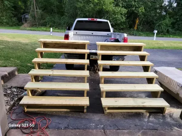 Two sets of wooden stairs in a parking lot behind a white pickup truck