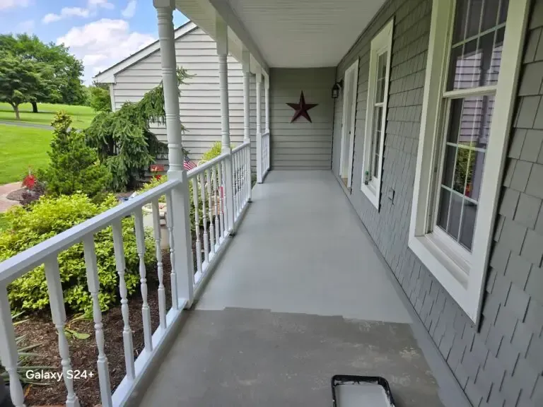 Covered front porch with white railing, gray floor, and red star wall decor.