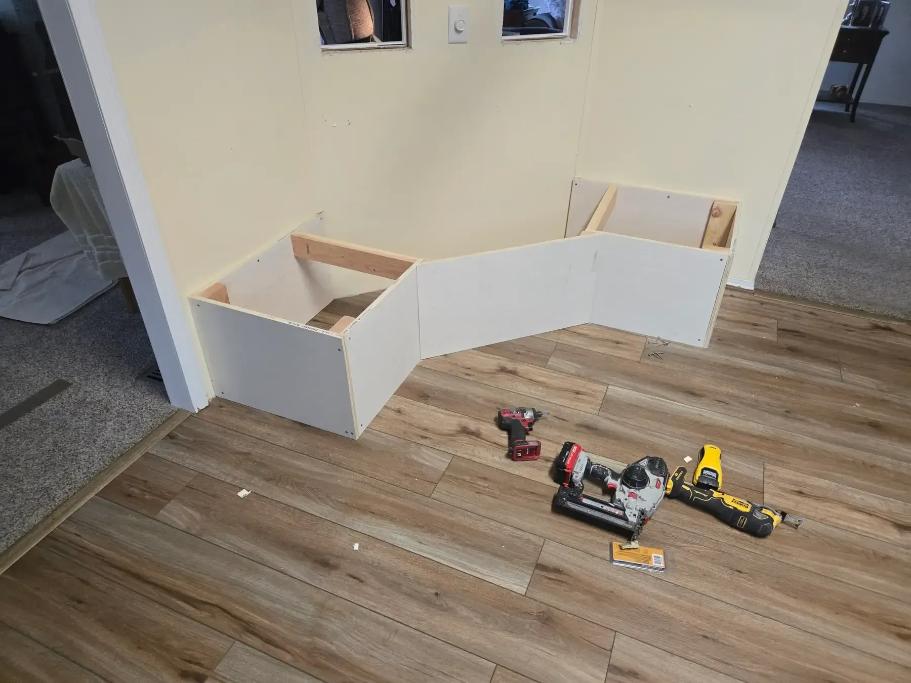 White playroom barrier with wooden floor and toy trucks and tools scattered nearby