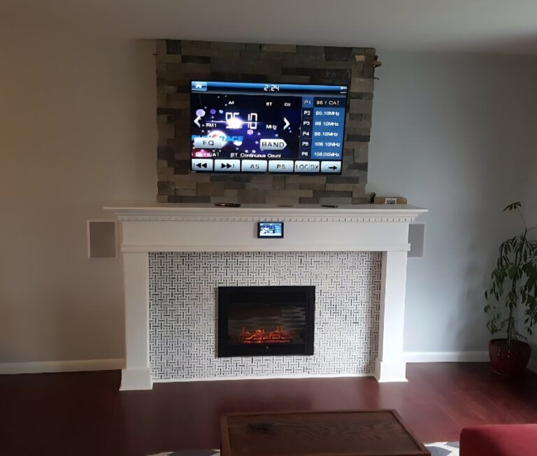 Living room with a white fireplace, wall-mounted TV, and small framed photo above the mantel.