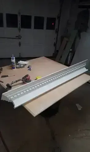 Long white fluorescent light fixture on a workbench in a garage, with tools nearby.