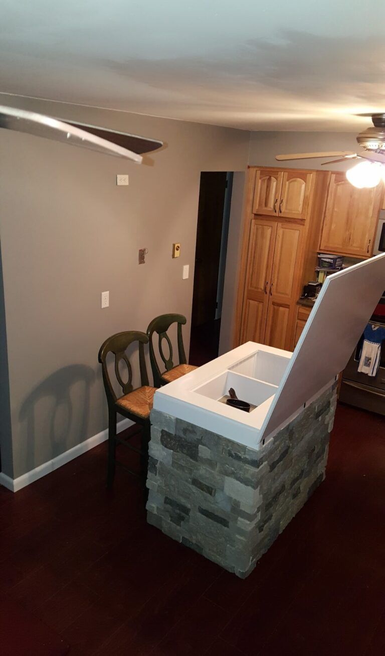 Interior hallway with dark wood floor, stone half-wall, and wooden cabinet/door in the background.