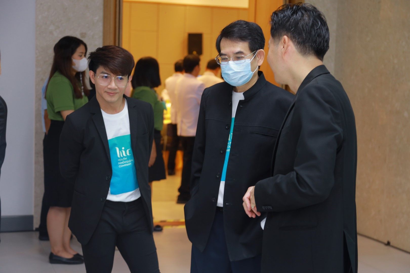 Three men wearing masks are standing next to each other in a room.