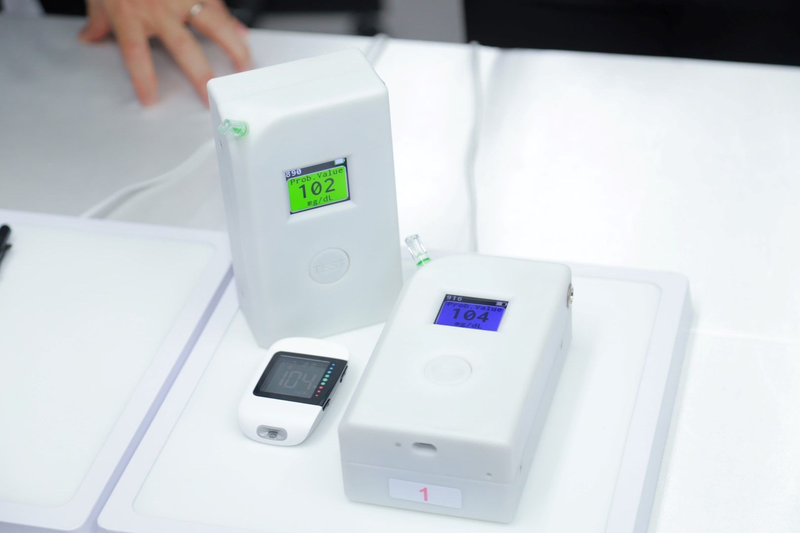 A white device with a green screen that says 102 on it