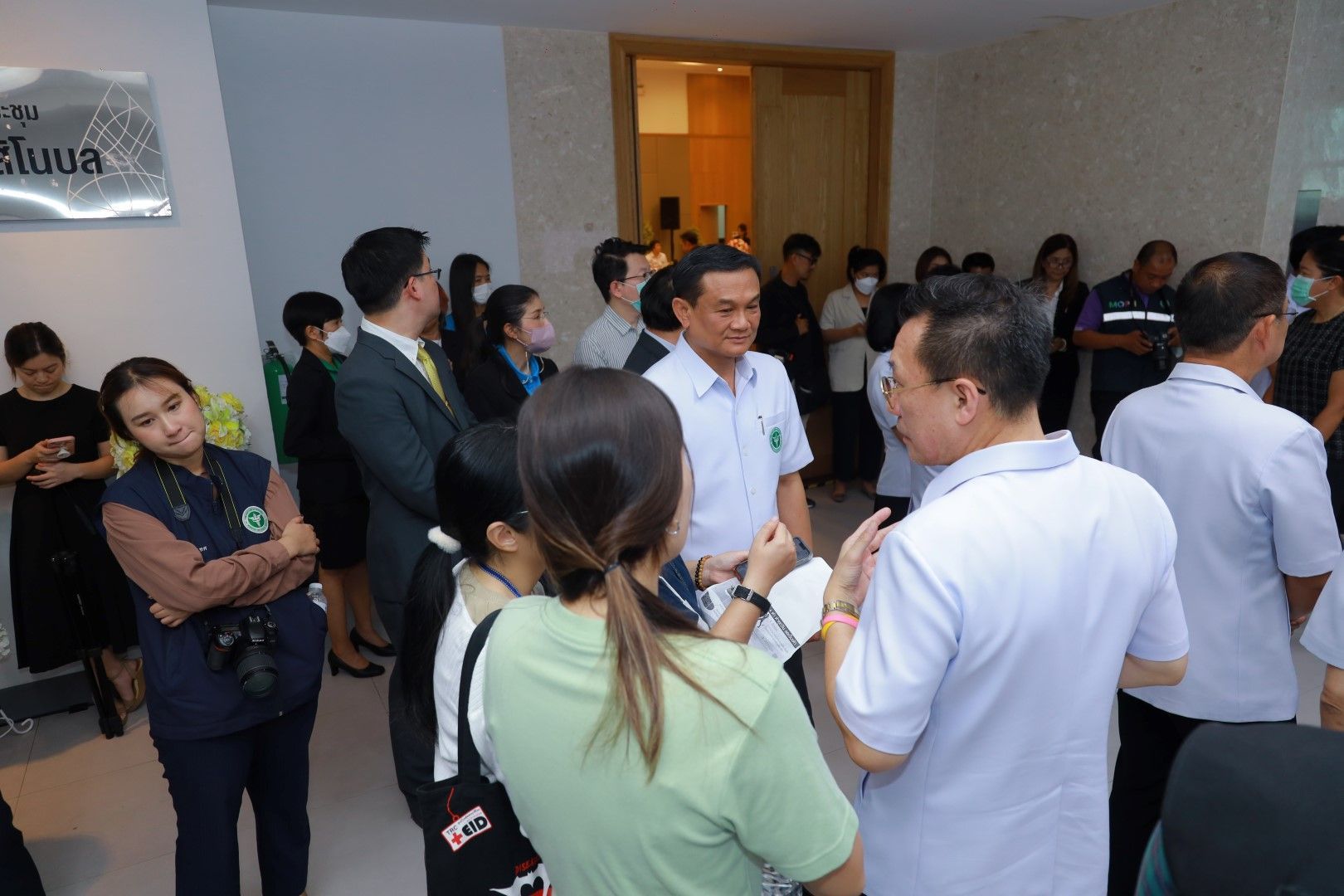 A group of people are standing in a room talking to each other.